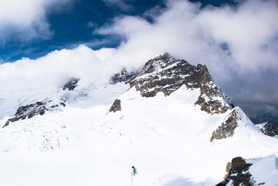 Scenic view of snowcapped mountains against cloudy sky