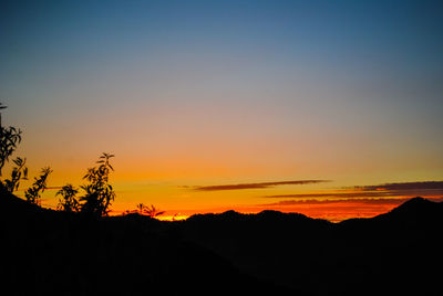 Scenic view of silhouette mountains against orange sky