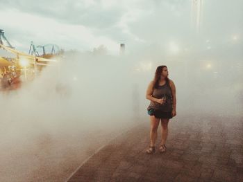 Full length of young woman standing in city against sky