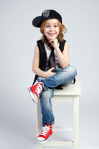 Portrait of smiling girl sitting against white background