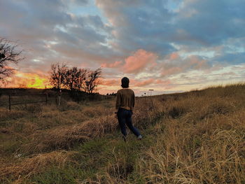 Rear view of man standing on field against sky