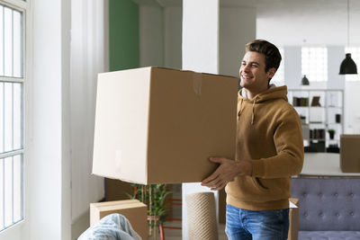 Full length of happy young man standing in box at home
