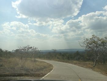 Road by trees against sky