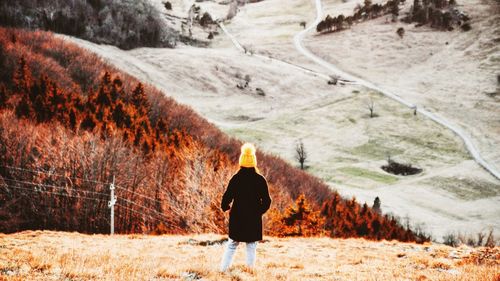 Rear view of woman walking on field