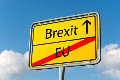 Low angle view of road sign against blue sky