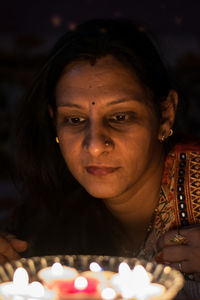 Woman looking at lit candles in darkroom