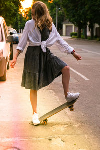 Rear view of woman skateboarding on road in city