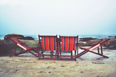 Empty chairs on beach against clear sky