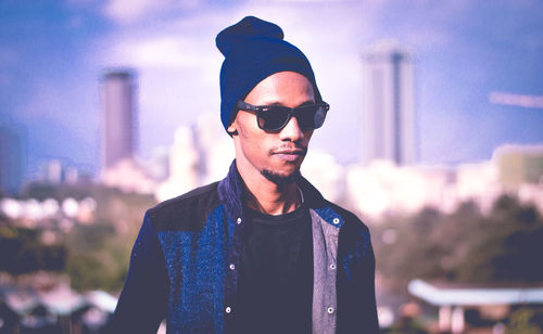 Portrait of young man wearing sunglasses standing against sky