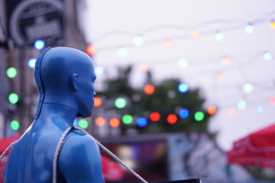 Close-up of statue against illuminated city