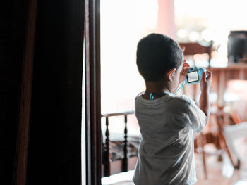 Rear view of boy looking through window
