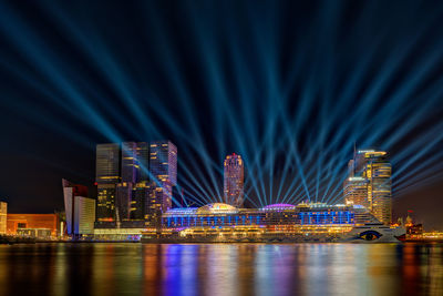 Illuminated city by river at night