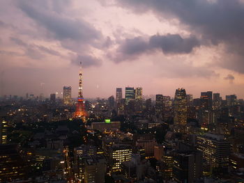 Illuminated cityscape against cloudy sky