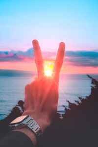 Midsection of person against sea during sunset