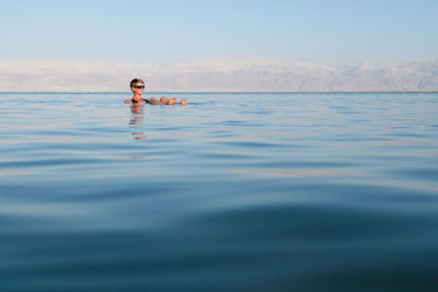 Woman relaxing in sea against sky