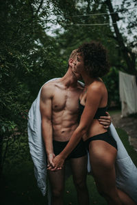 Young couple standing against trees