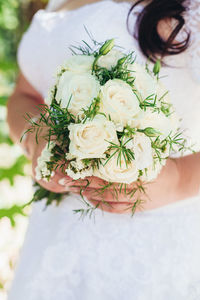 Midsection of bride holding rose bouquet