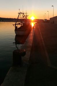 Silhouette boat moored on sea against sky during sunset