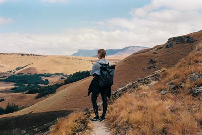 Rear view of man standing on mountain against sky