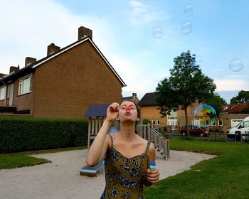 Young woman blowing bubbles at playground in town