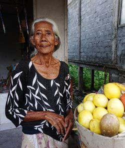 Portrait of woman standing by fruits