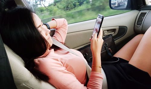 Midsection of woman using mobile phone in car