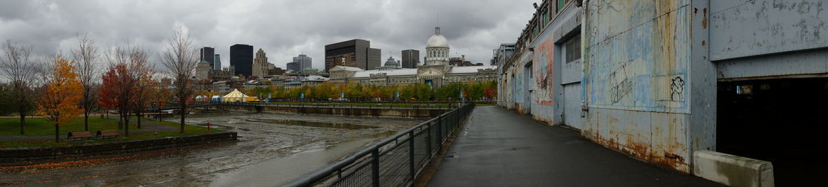 Panoramic view of wet street amidst buildings against sky