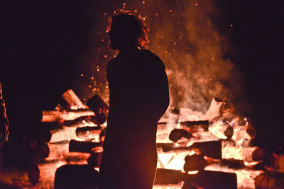 Silhouette man standing against bonfire at night