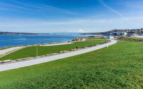 Scenic view of field by sea against sky