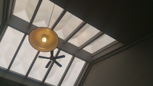 Low angle view of electric lamp hanging on ceiling up above angles light