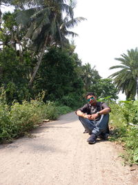 Portrait of man sitting on road against trees