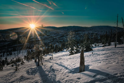Scenic view of snow covered landscape against bright sun