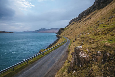 Scenic view of road by sea against sky