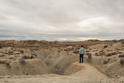 Rear view of man walking on landscape against sky