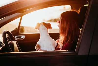 Woman with dog sitting in car