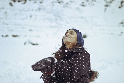 Woman in warm clothing playing with snow