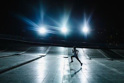 Full length of man running at illuminated city at night