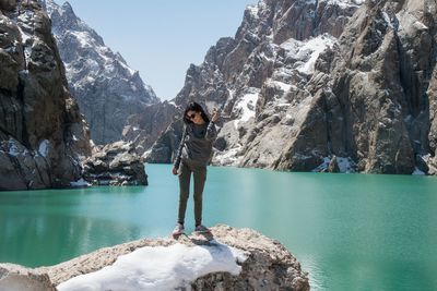 Full length of woman standing on rock by lake