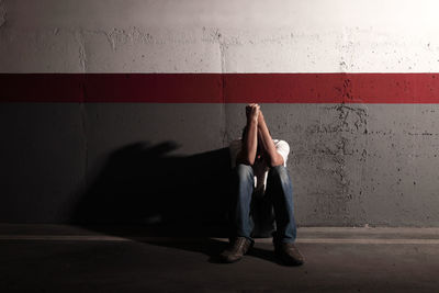 Full length of sad man sitting on street in tunnel