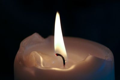 Close-up of lit candle against black background