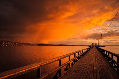 Pier on sea against cloudy sky