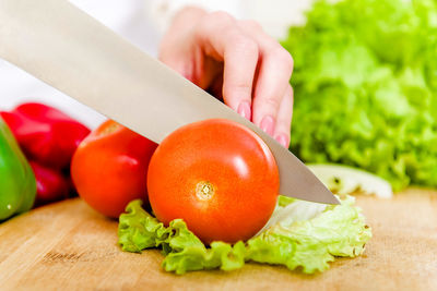 Cropped hand of woman cutting tomato