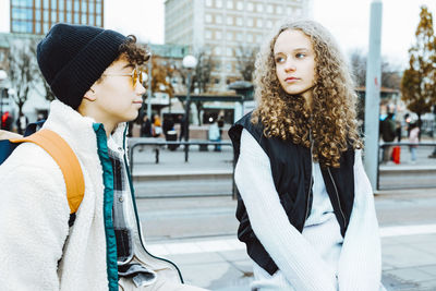 Girl talking with male friend while hanging out in city during weekend