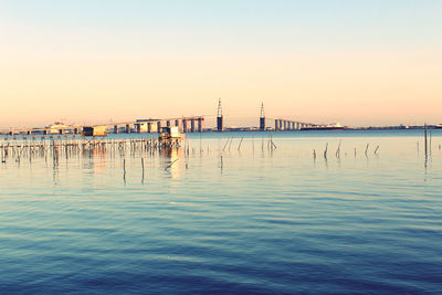 Wooden posts in sea at sunset