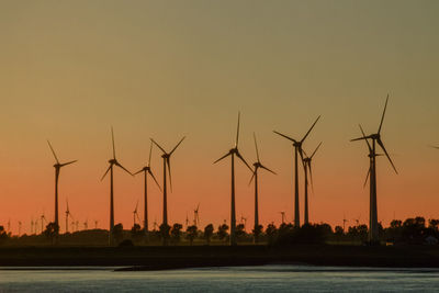 Silhouette cranes against sky during sunset