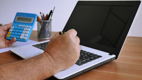 Midsection of man using laptop on table