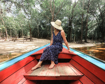 Woman sitting in boat against trees