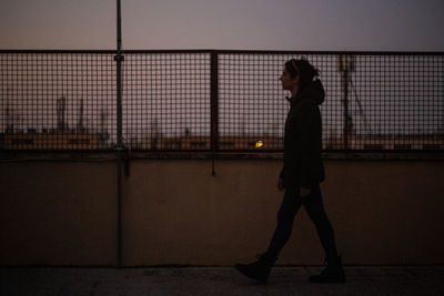 Side view of silhouette woman standing against wall at night