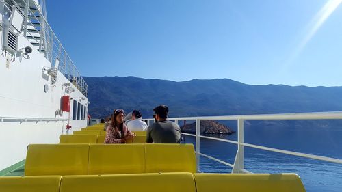 People sitting on mountain against clear blue sky