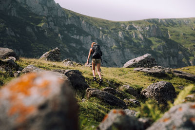 Low angle view of female hiker with backpack walking on mountain